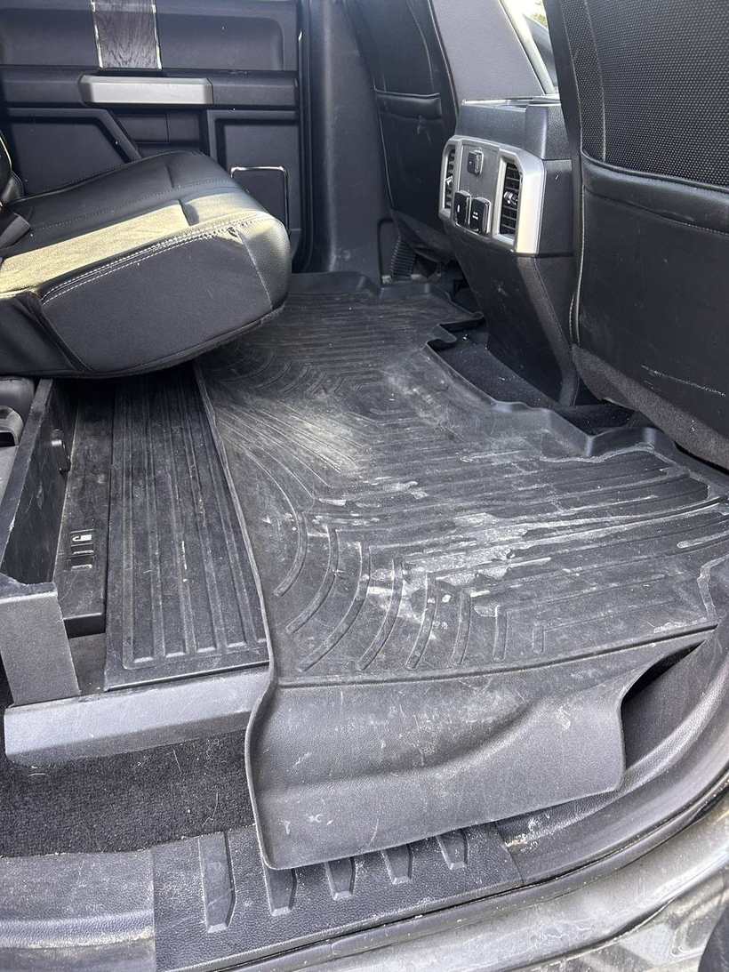 Before — dusty, salt-stained floor mats in a truck rear footwell